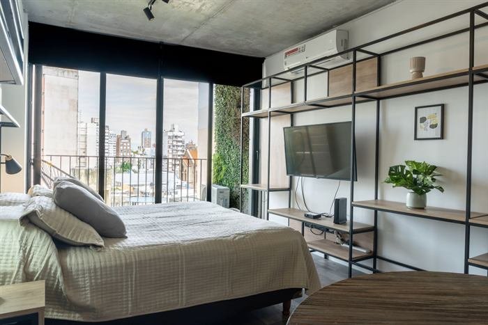 Dormitorio con ventanal de piso a techo y estantería metálica en la propiedad de Fernando