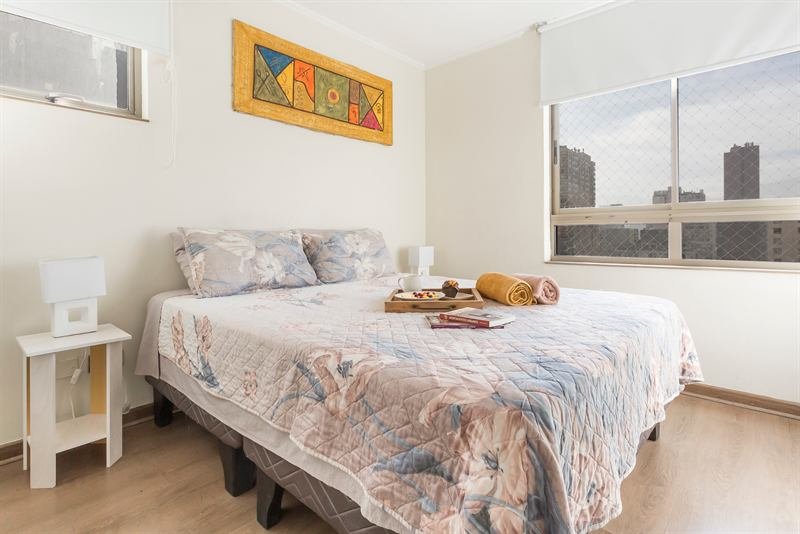 Dormitorio de la propiedad con cama doble, ropa de cama preparada y vista a la ciudad