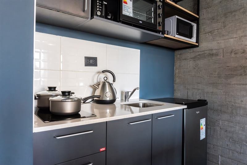 Cocina equipada con muebles grises, pared azul y hormigón a la vista