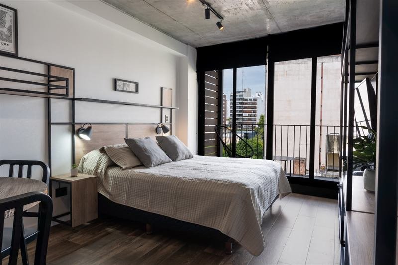 Dormitorio con ventanales de piso a techo, estructura metálica y vista a la ciudad